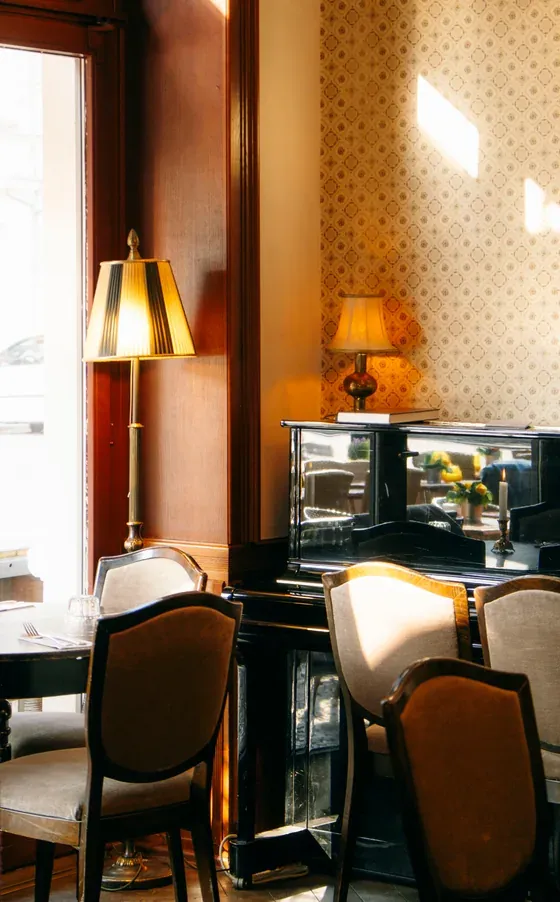 Dining room by the window with table lamps, patterned wallpaper and a laid table