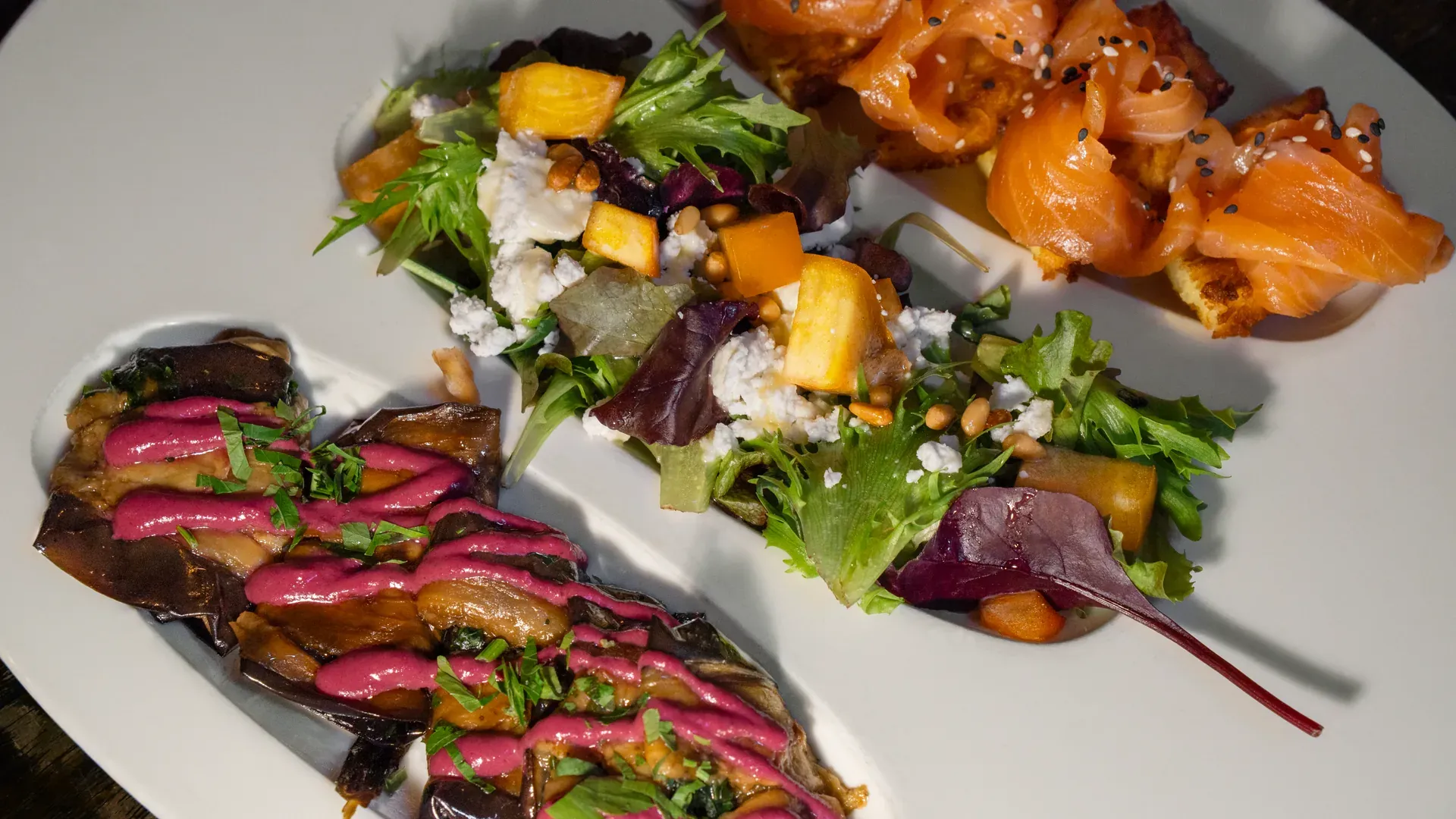 Salad with goat cheese and pomegranate, smoked salmon and marinated aubergines alongside